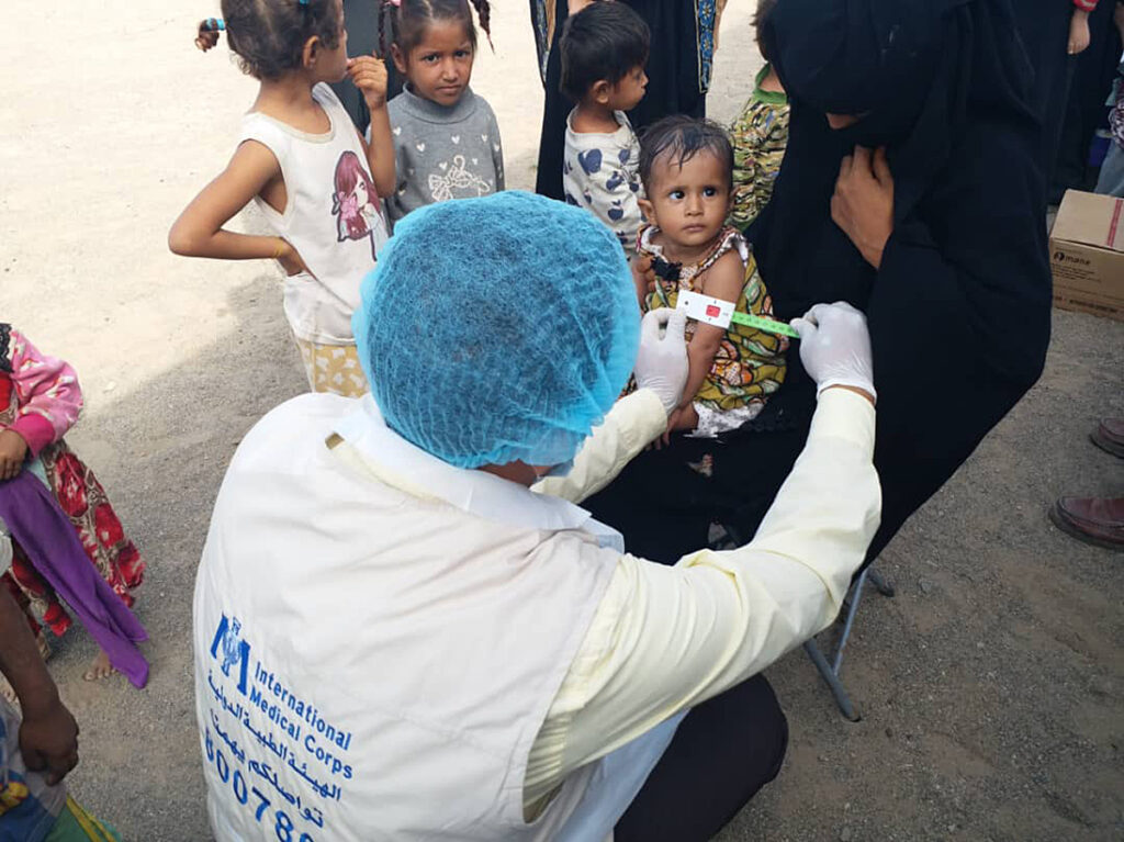 A member of International Medical Corps mobile medical unit measures a young child for malnutrition in a remote area of Sana’a Governorate.