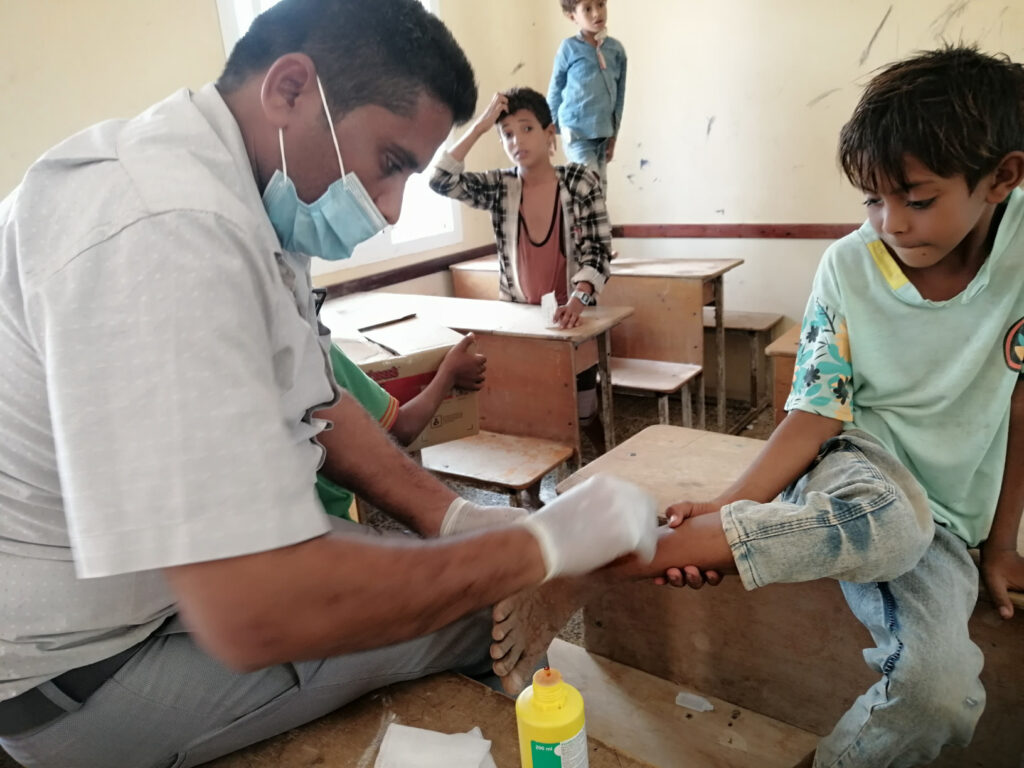 A member of International Medical Corps' mobile medical unit cleans and treats a minor leg wound for a child in a remote area of Sana’a governorate. In such locations, our mobile teams are often the only source of healthcare available to local residents.