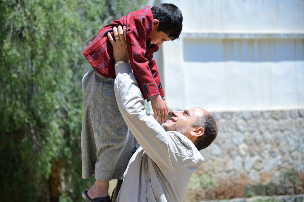 As new equipment and supplies are carried into the refurbished health clinic, the orphanage’s resident manager lifts a small boy in the air amid the excitement.