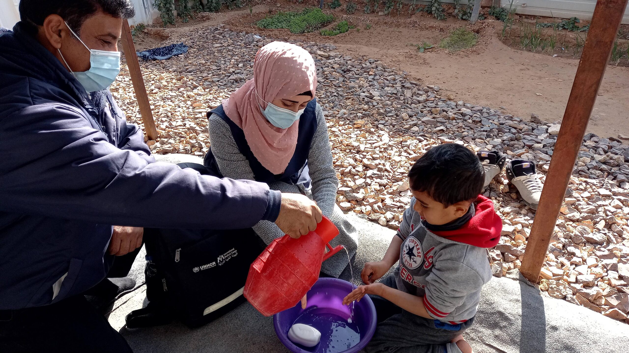 Eman, community health officer, teaching a little boy proper handwashing techniques.