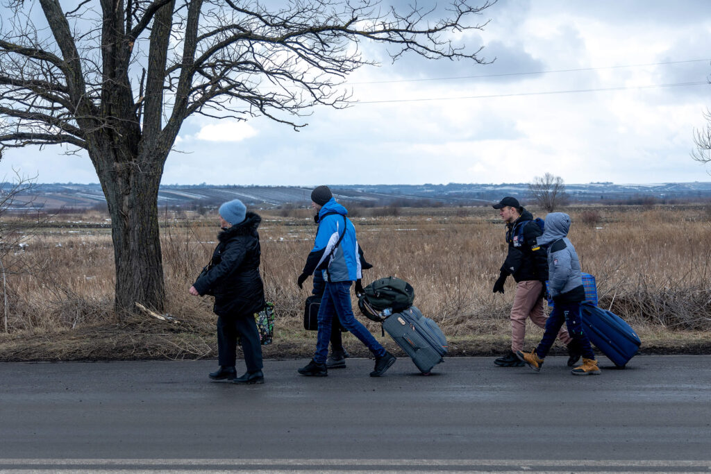 A group of Ukrainian refugees walk on the roadside after crossing the Siret border crossing on their way to buses chartered in Romania to take them to accommodations in neighboring villages or to different cities in Romania.