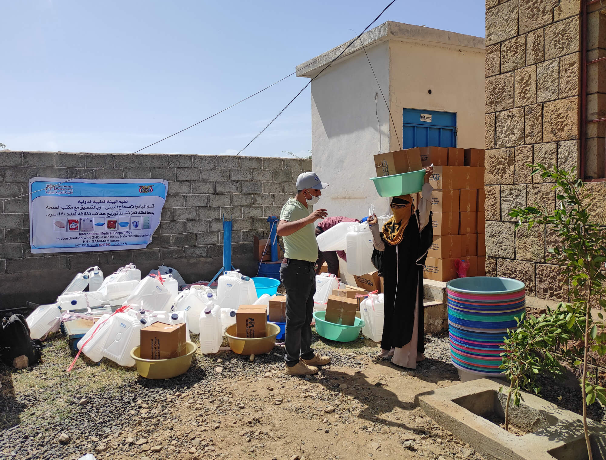 A WASH staff member distributes hygiene kits to a woman in Yemen.