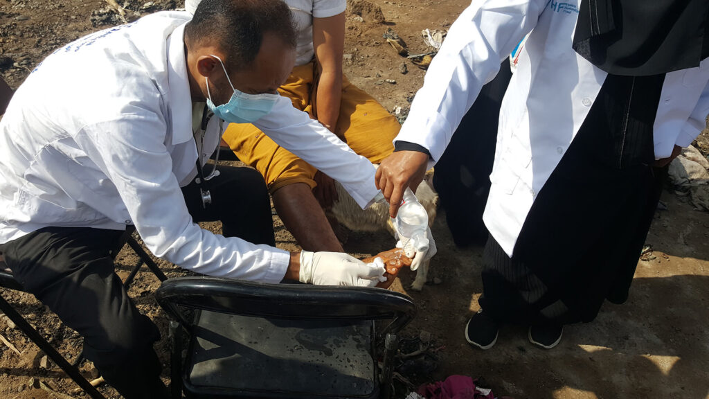 A mobile team staff member treats an Al Qahera camp resident injured during a fire.