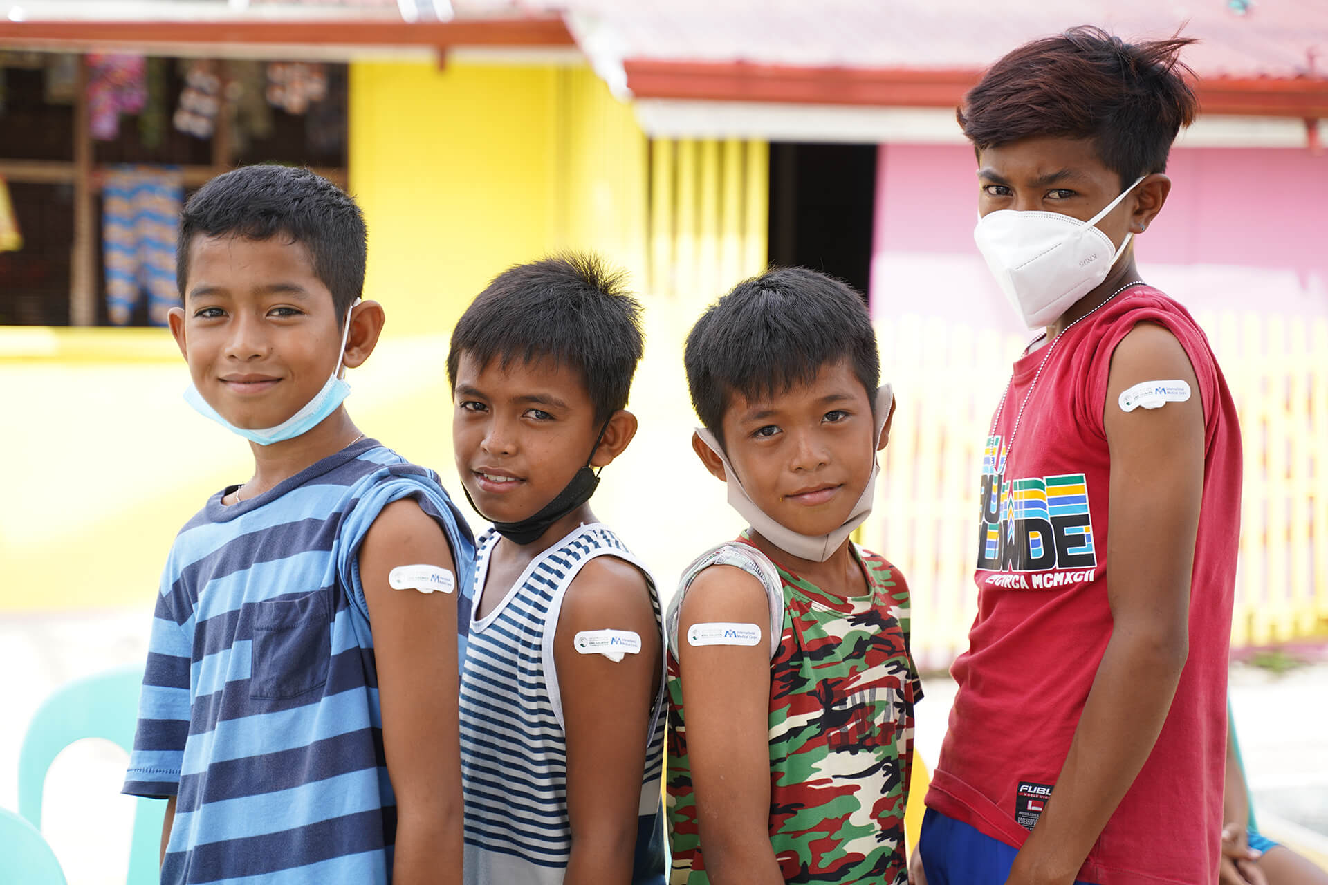 Four boys proudly show off their International Medical Corps bandages after being vaccinated against COVID-19.