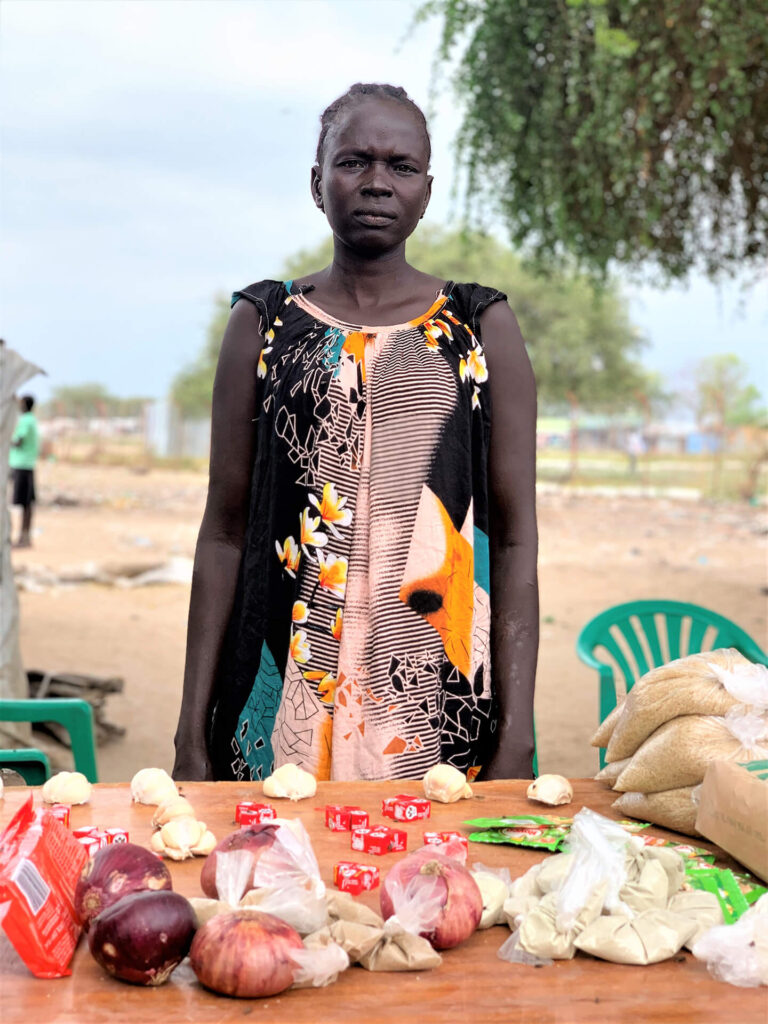 Deborah Adhieu Manyok stands behind her shop in Panyagor, South Sudan.
