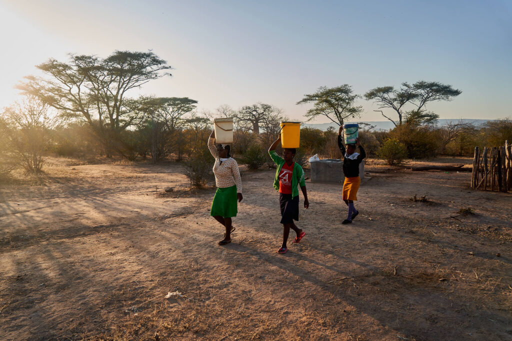 Siangwemu villagers balance buckets of water on their heads as they return from the community pump.