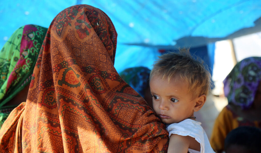 Pathani holds her son, Sajjad, on their visit to the International Medical Corps mobile medical clinic.