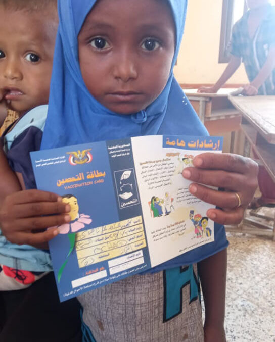 Shahid, a young resident of Al-Samasim village in Al Mukha district, proudly holds up her certificate of vaccination against measles after receiving her inoculation.