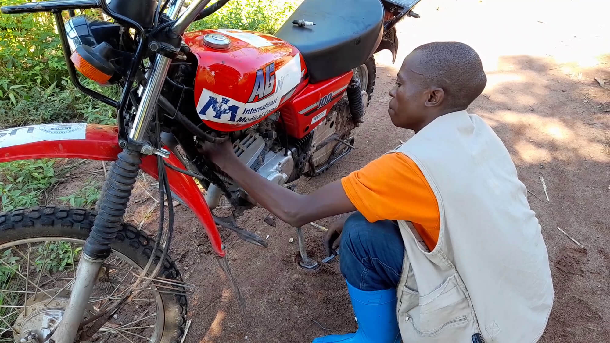 Djaile tries to repair a motorbike in the field when it refuses to start up.