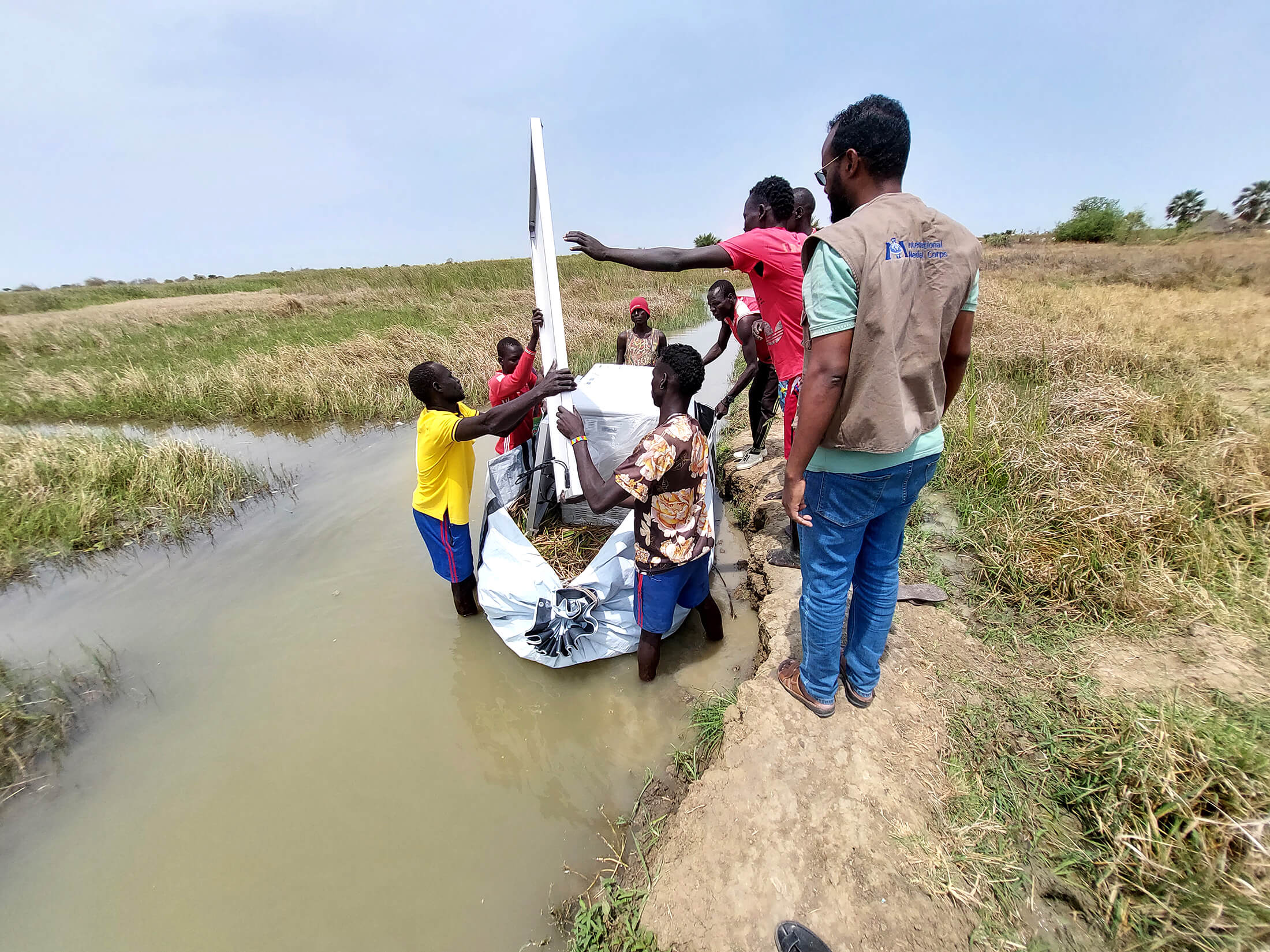 Ahmed-kheyr Moalim Mohamud helps a group of porters transport a vaccine refrigerator on an improvised canoe.