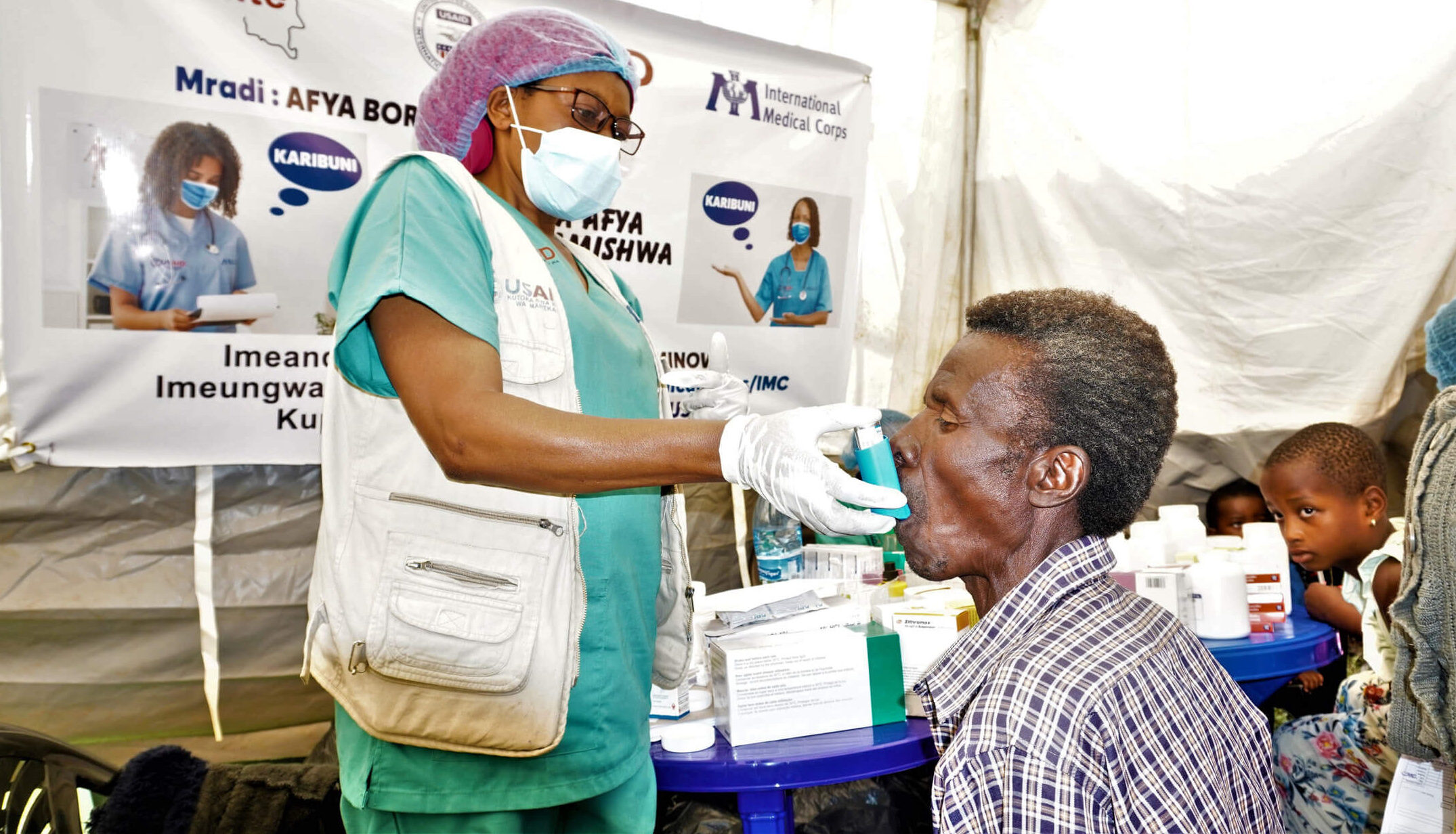 Nurse Esperance helps patient Juvénal Shukuru with his asthma medication.