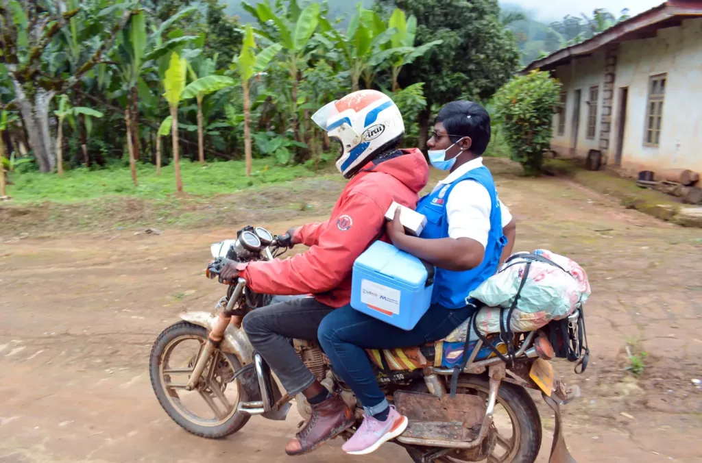 Bertha hires a motorbike to travel to Oshie. It is the only available transportation in that area, due to conflict and poor road conditions.