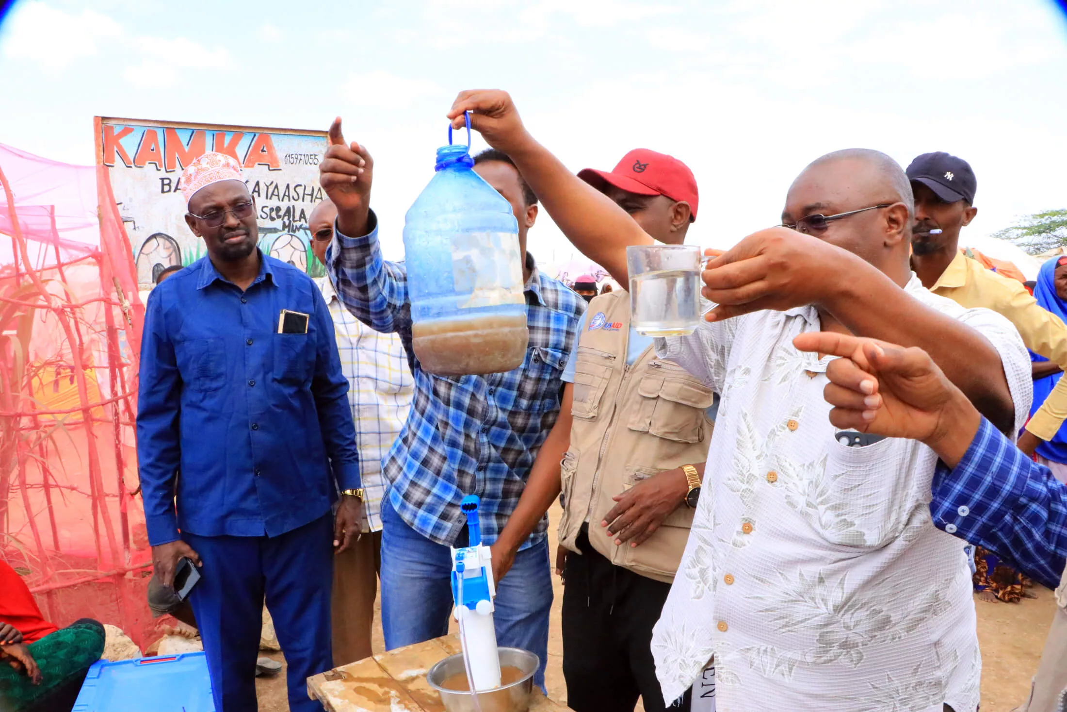 Staff members demonstrate how the water purifier works as families listen and receive their water survival boxes.