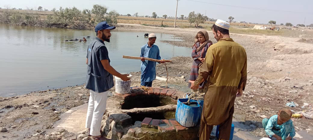 Community Mobilizer Arshad Ali Sodhro helps flood-affected villagers learn how to use water purification tablets.