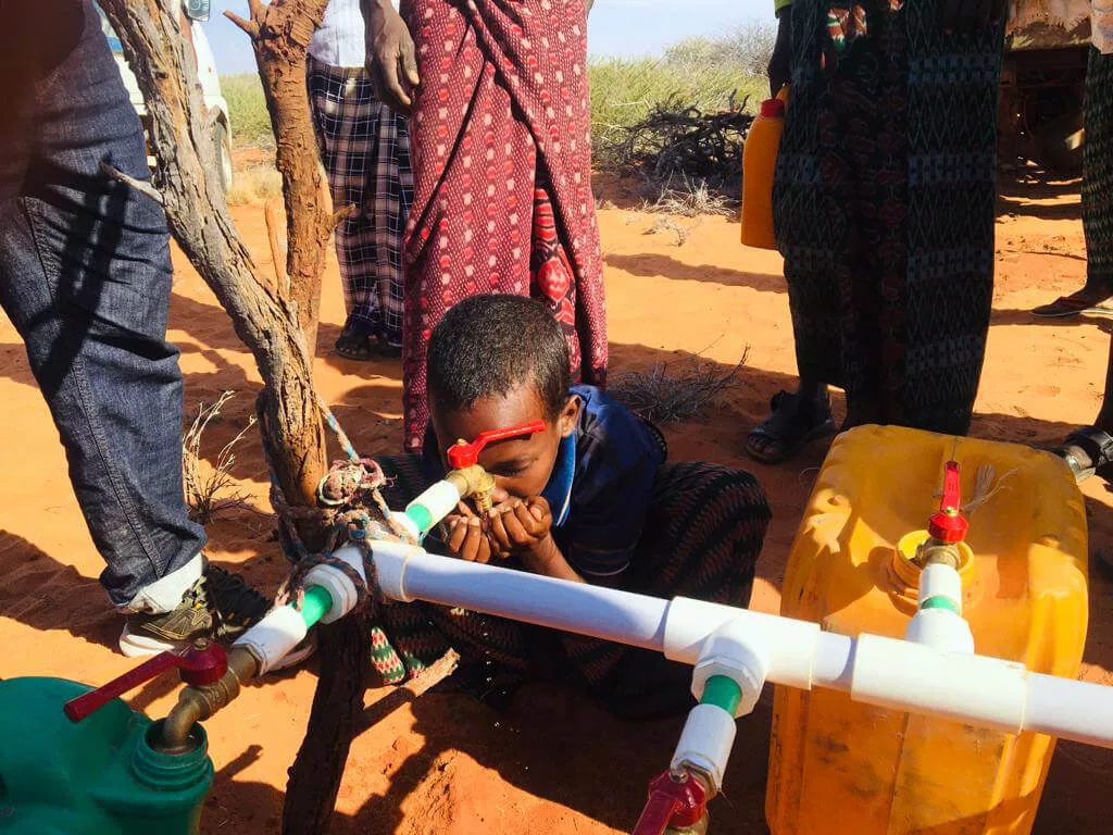 A young boy drinks from a water source we constructed.