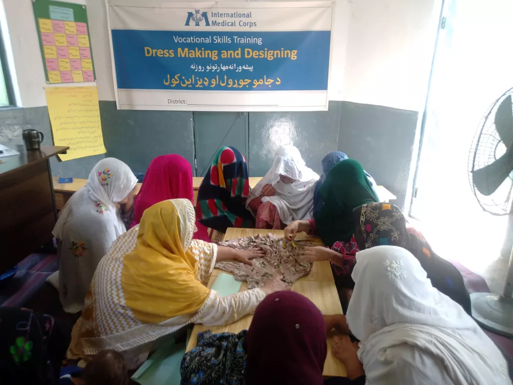Nadia and other women in her tailoring course learn dressmaking in the refugee village of Khaki, Pakistan.
