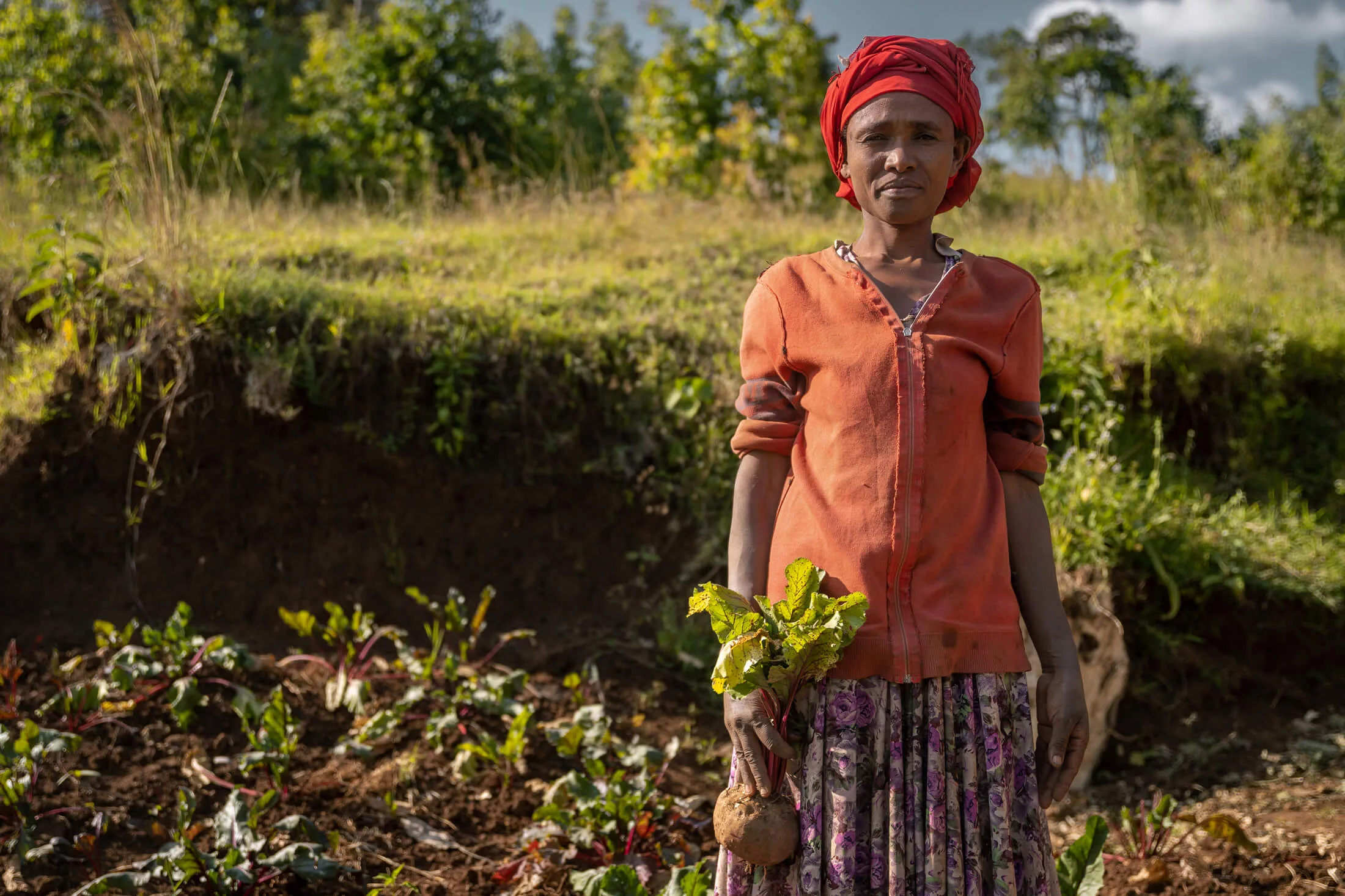 Eshale stands in her garden, where she’s learned to grow a variety of crops that support her family’s health and nutritional needs.