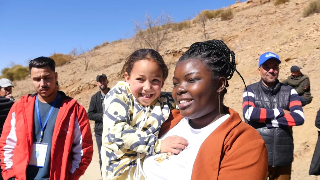 Staff member Dorah Lwanzo Kavira holds a child at the distribution site in the Ouneine region of Taroudant province, where our team provided winterization kits and hygiene kits to earthquake-affected families.