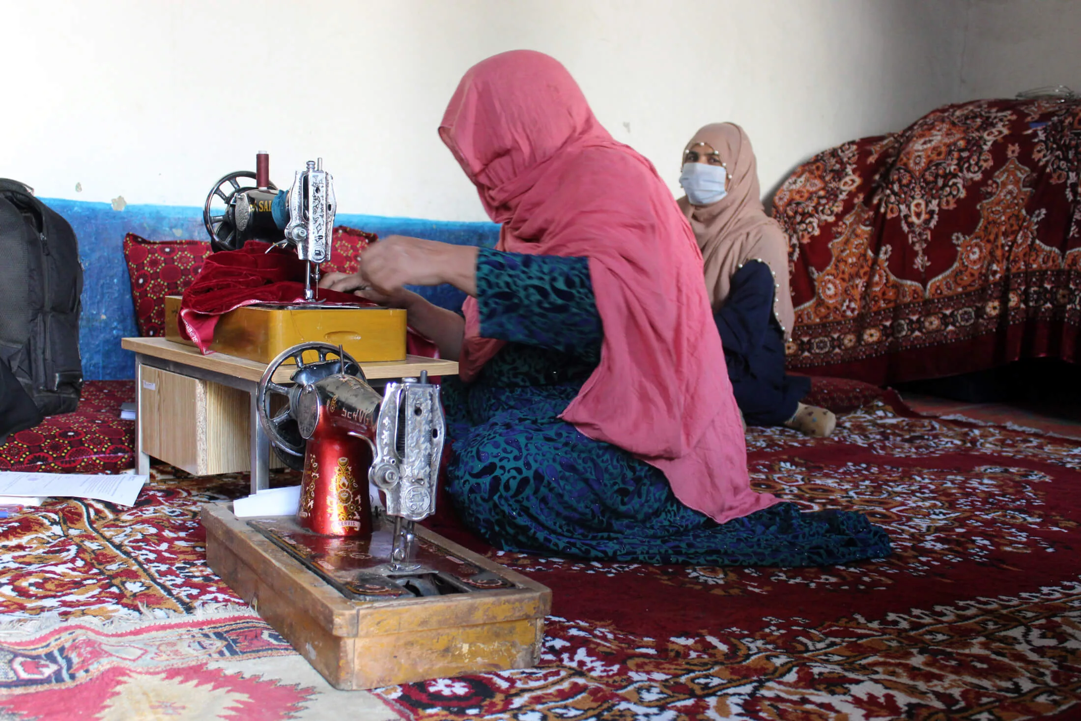 Gulmeena works at her sewing machine in the refugee village of Padhana, Pakistan.