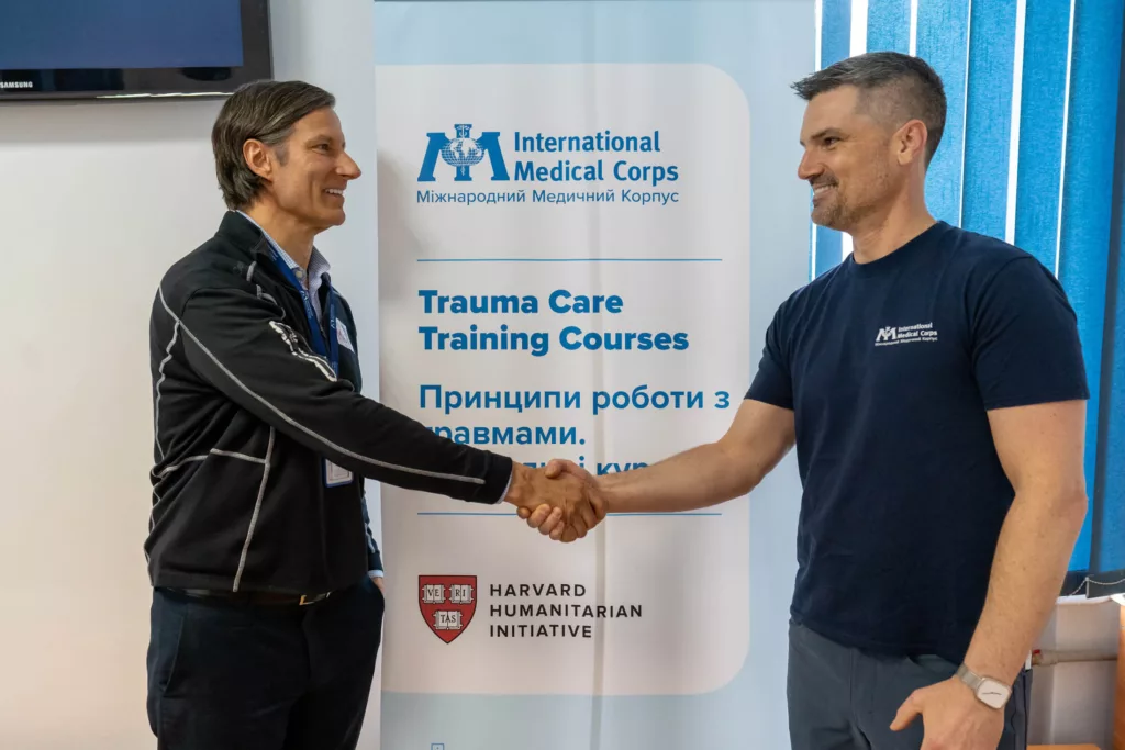 Ukraine Country Director Matthew Stearns (right) shakes hands with Harvard Humanitarian Initiative Director Michael Van Rooyen.