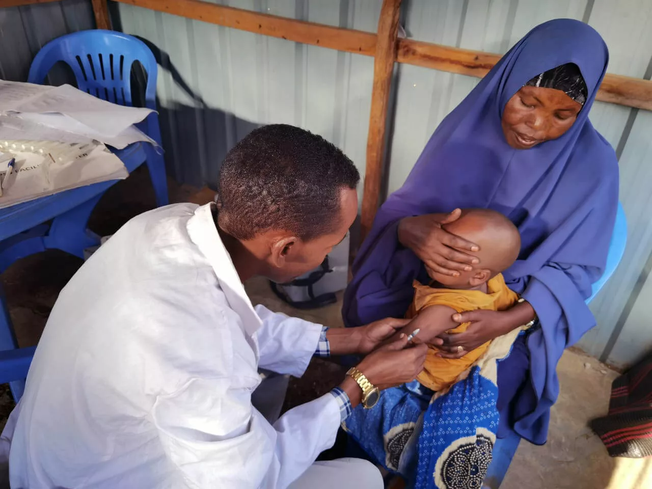 Mu’ad Isak Barre sits in his mother’s lap while receiving a vaccine from an International Medical Corps team member in Somalia.