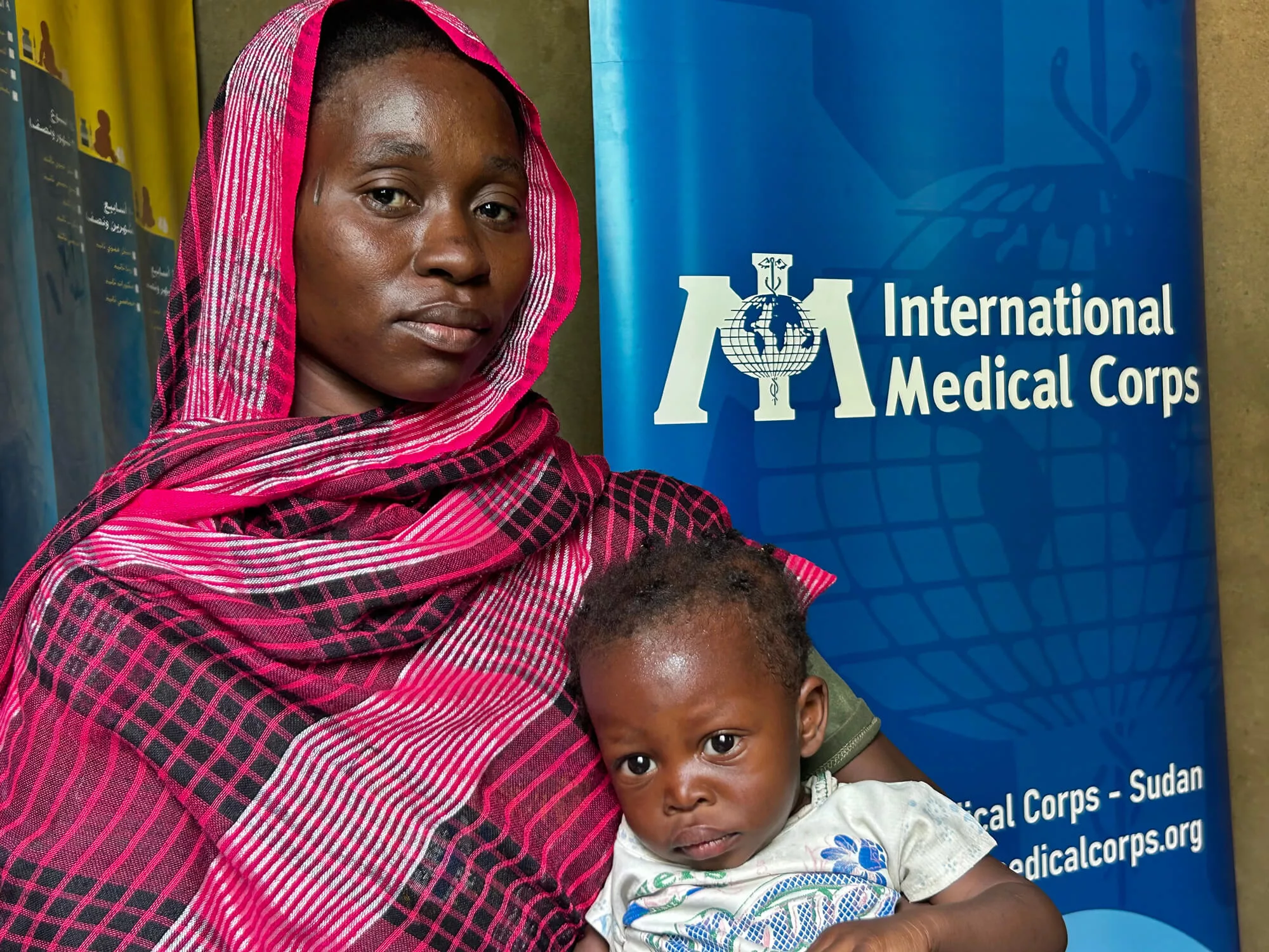 Nafeesa Mustafa sits with her son, Ahmed, in her lap at the Murafaa Althany Clinic in Sudan.