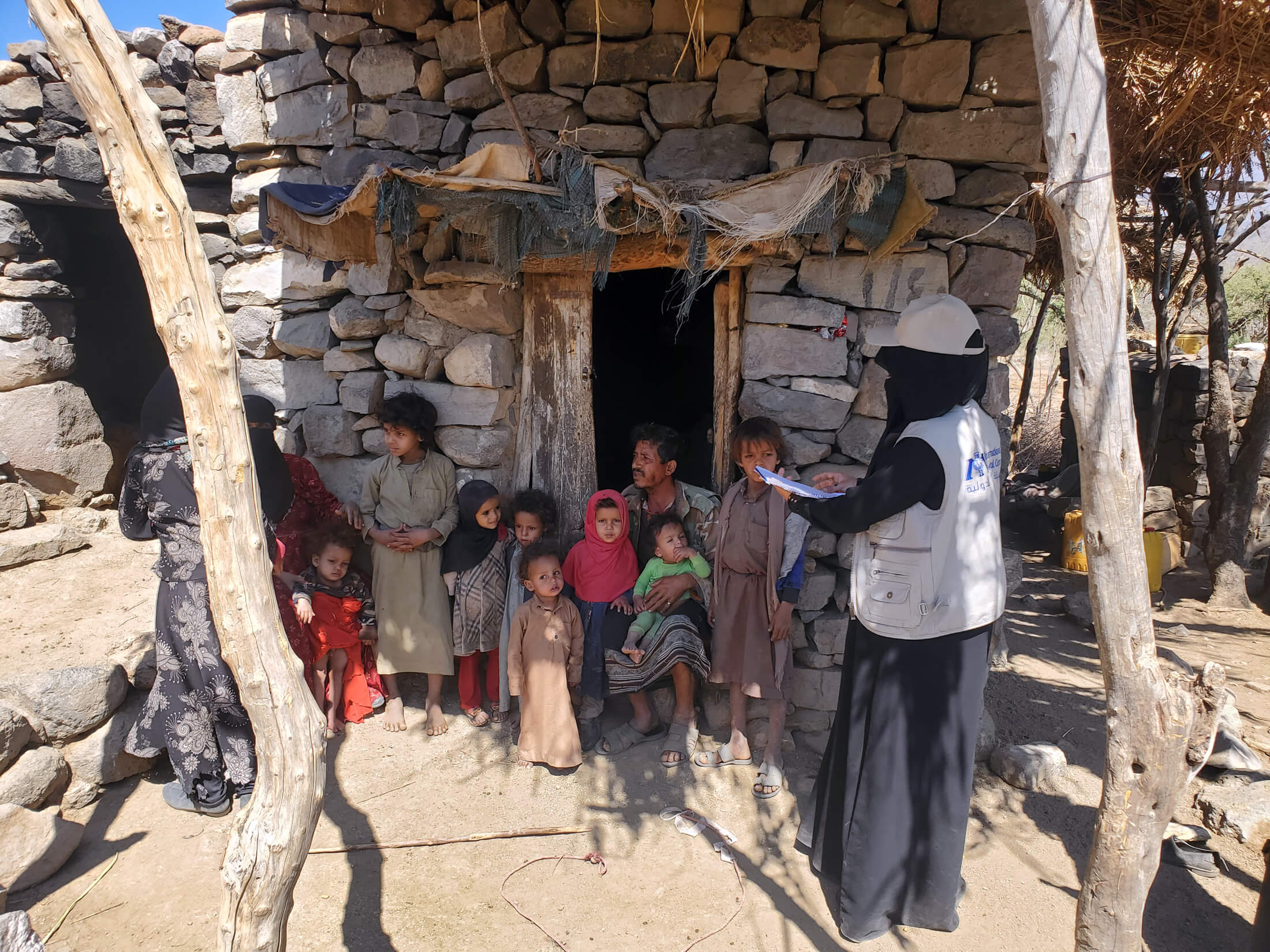 An International Medical Corps community health worker speaks to Nawaya’s family outside their home in Al Qafr.