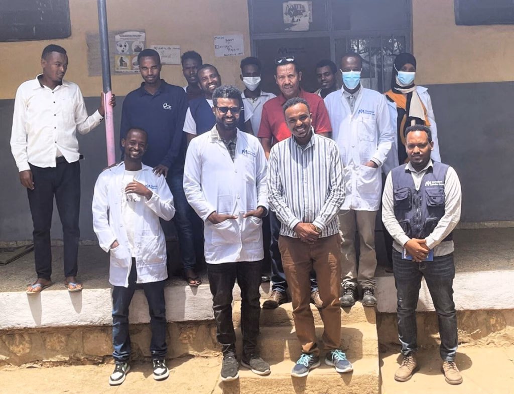 Henock Million (bottom right, in vest) visits an International Medical Corps field team in Oromia region in June 2024.